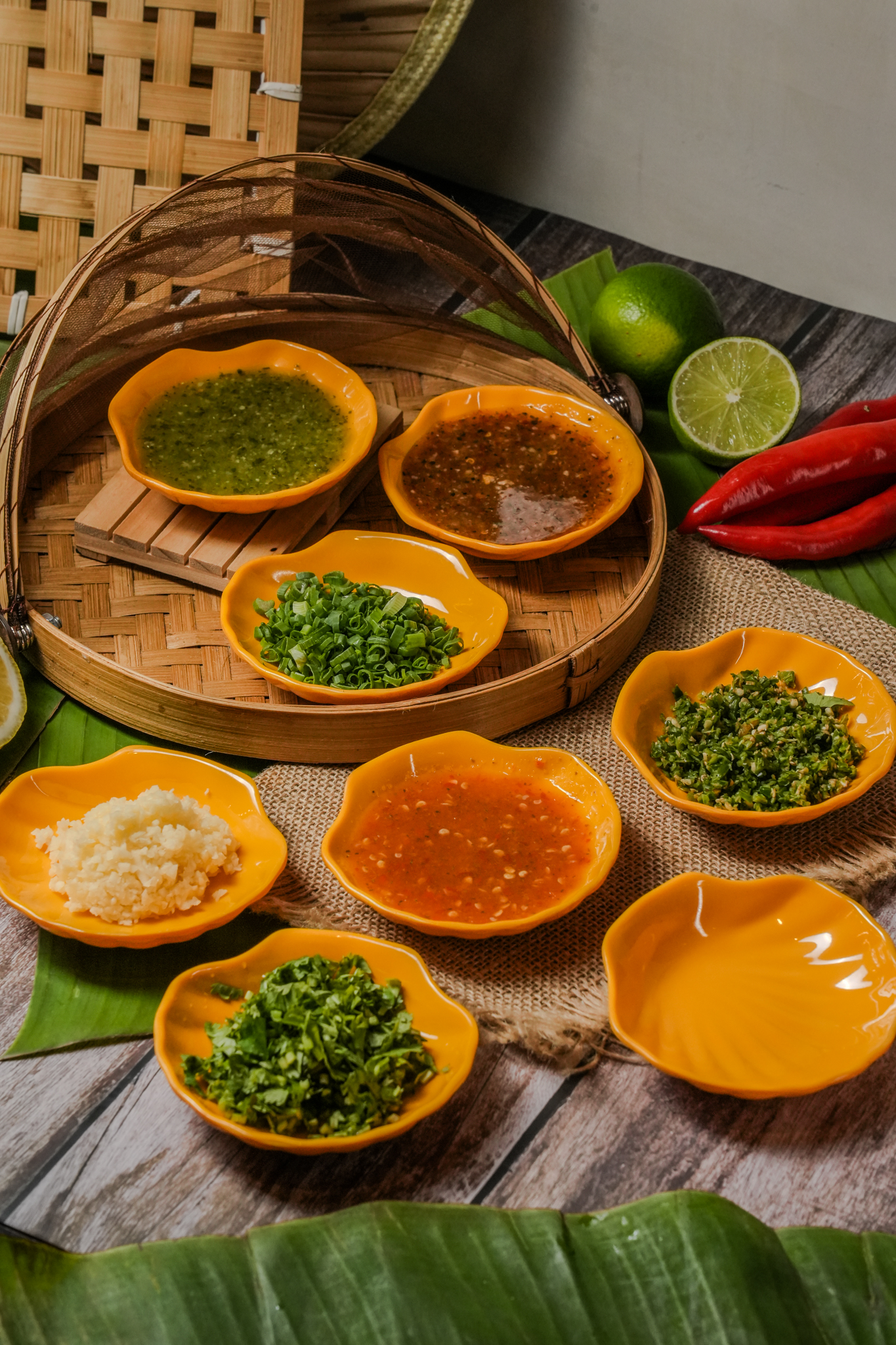 Thai dipping sauces in yellow ceramic bowls with banana leaf and bamboo basket